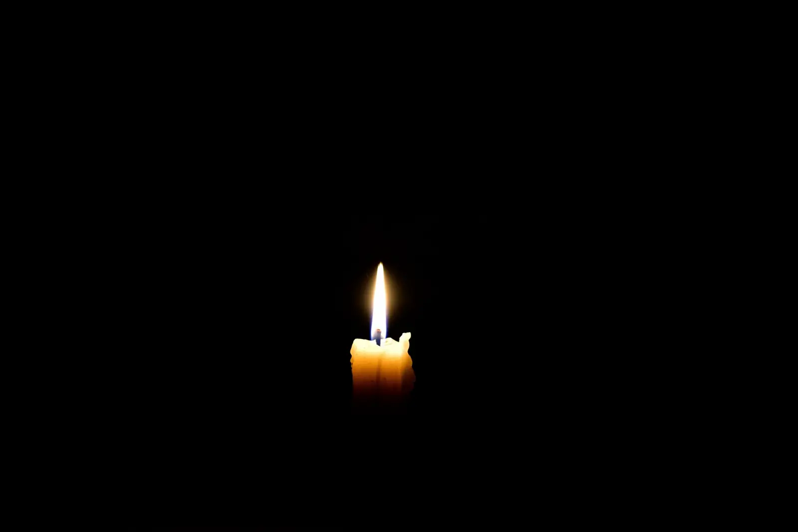 A single memorial candle burning in the dark